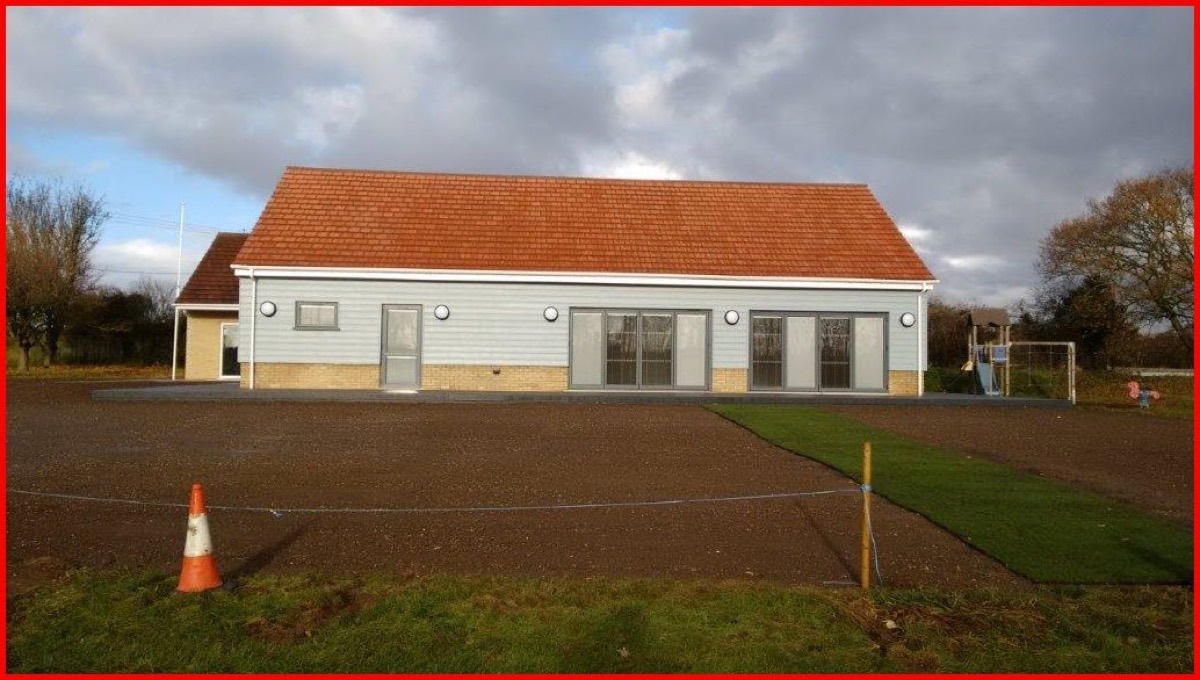 Kentford and Kennett Village Hall: a single storey building with a long pitched roof and wide windows, seen from the playing field.