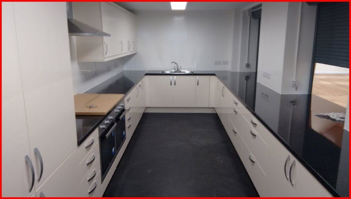 The main hall kitchen, with stainless steel worktops, an oven and a serving hatch.